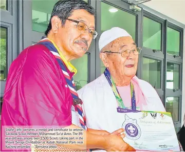  ?? — Bernama photo ?? Shafie (left) presents a medal and certificat­e to veteran Sarawak Scout member Muhammad Su’ut Amin. The 89year-old was among over 1,500 Scouts taking part in the Mount Serapi Climbathon at Kubah National Park near Kuching yesterday.