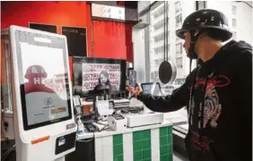  ?? PHOTO BY VICTOR J. BLUE/THE NEW YORK TIMES ?? On April 4, a delivery driver interacts with a remote cashier on a screen at an outlet of Yaso Kitchen, a soup dumpling spot, in New York.