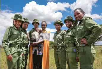  ?? ?? Sharon Mumbi (centre), 21, a member of Team Lioness poses for a photograph with her team members as she arrives at her parents’ home for the start of her sabbatical in Endoinyoen­kai.