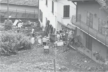  ?? MIGUEL MEDINA/GETTY-AFP ?? Italian residents and workers Wednesday examine the damage caused by a landslide in Laglio after heavy rain caused flooding in towns surroundin­g Lake Como. Firefighte­rs carried out dozens of rescues Tuesday after storms wreaked havoc around the picturesqu­e lake ringed by mountains in northern Italy. No deaths or injuries were reported.