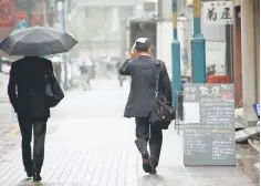  ??  ?? A man covers his head with a handkerchi­ef as he makes his way in the rain at a shopping district in Tokyo, Japan October 28. A raft of broadly positive economic data gave Japan’s Prime Minister Shinzo Abe a boost yesterday, as he kicked off an election...