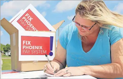  ?? MILLICENT MCKAY/JOURNAL PIONEER ?? Heather Ford, spokespers­on for PSAC P.E.I. chapter, signs a postcard that will be sent to MP Scott Brison asking for the Phoenix pay system to be fixed.