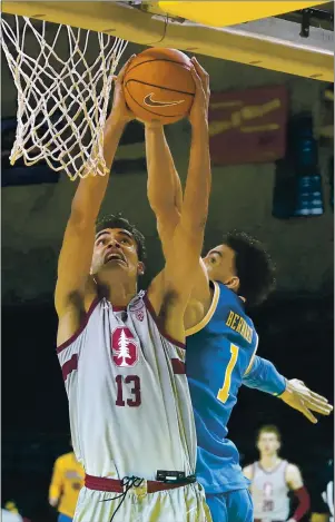  ?? PHOTOS BY TONY AVELAR — THE ASSOCIATED PRESS ?? Stanford forward Oscar da Silva scores while being defended by UCLA guard Jules Bernard in the final seconds of overtime in the teams’ Pac-12 Conference game at Kaiser Permanente Arena in Santa Cruz on Saturday.