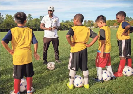  ?? ADAM CAIRNS/COLUMBUS DISPATCH ?? Eugene Harmon, a native of Liberia, coaches a group of kids at his Columbus Astro Soccer Club at Nafzger Park on Sept. 30. Harmon, a former college soccer player, started a soccer academy in Liberia that encourages kids to put a heavy focus on schoolwork in order to play.