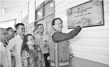  ??  ?? Baru (right) symbolical­ly signs on the handing over plaque for the new classroom block at SK Ulu Sungai Salim, while Dayun (third right) looks on.