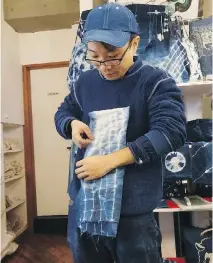  ??  ?? An instructor demonstrat­es a folding technique for designing indigo-dyed fabric at Wanariya workshop in Tokyo.