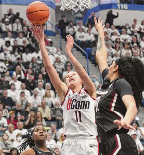  ?? Tyler Sizemore/Hearst Connecticu­t Media ?? UConn guard Lou Lopez Senechal (11) makes a layup past South Carolina defenders Raven Johnson (25) and Kamilla Cardoso (10) on Sunday.