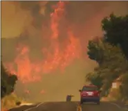  ?? MIKE ELIASON — SANTA BARBARA COUNTY FIRE DEPARTMENT VIA AP ?? This Saturday photo released by the Santa Barbara County Fire Department shows a Santa Barbara City Fire vehicle on Highway 154 in the Whittier fire east of Cachuma Lake in Santa Barbara County Wildfires barreled across the baking landscape of the...