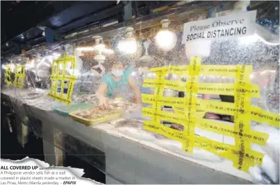  ??  ?? ALL COVERED UP ...
A Philippine vendor sells fish at a stall covered in plastic sheets inside a market in Las Pinas, Metro Manila yesterday. – EPAPIX