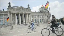  ?? SEAN GALLUP / GETTY IMAGES FILES ?? Visitors ride bicycles past the Reichstag in Berlin. Russia is building a small-scale replica of the building in Moscow’s Patriot Park for children to storm.