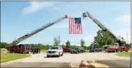  ?? KRISTI GARABRANDT — THE NEWS-HERALD ?? The hearse carrying the casket with Michael Palumbo Jr. passes into the cemetery under crossed aerials. The crossed ladder with the flag suspended is symbolic of a fire fighter’s passing into the next life.