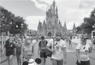  ?? Orlando Sentinel/tns ?? Guests wear masks. as required. to attend the official re-opening day of the Magic Kingdom at Walt Disney World in Lake Buena Vista, Florida, on July 11.