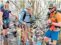  ?? CLAIRE JARVIS ?? Florida Trail thru-hikers, from left, Megaman, Model and Bear Magnet, navigate a swampy section of trail, getting feet wet along the way.