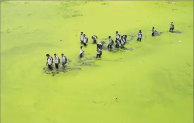  ?? SUVRA KANTI DAS / SPLASH NEWS ?? A group of students walk through polluted water in Dhaka, Bangladesh.