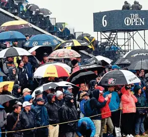  ?? GETTY IMAGES ?? Weather the storm: spectators take cover at the sixth