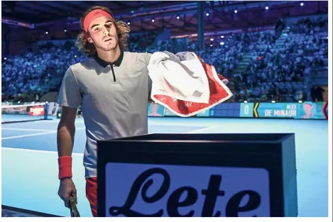  ?? — AFP ?? Playing to new rules: Greece’s Stefanos Tsitsipas places his towel in a rack during the men’s final of the Next Generation ATP Finals in Milan on Saturday, as a new rule stipulates players have to get their own towels from a rack courtside with no ball-kids to run for them.