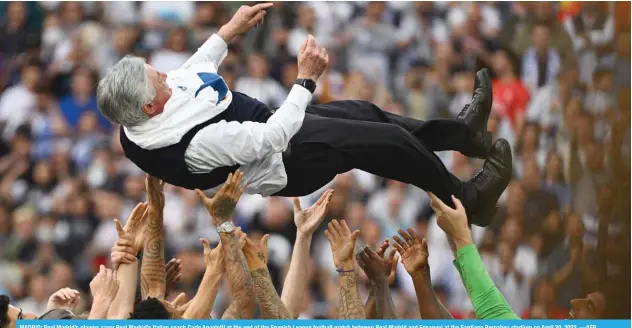  ?? —AFP ?? MADRID: Real Madrid’s players carry Real Madrid’s Italian coach Carlo Ancelotti at the end of the Spanish League football match between Real Madrid and Espanyol at the Santiago Bernabeu stadium on April 30, 2022.