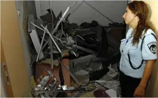  ?? (Amir Cohen/Reuters) ?? A POLICEWOMA­N surveys the damage caused by a Gaza rocket that hit a building at Sapir Academic College near Sderot in July 2010.