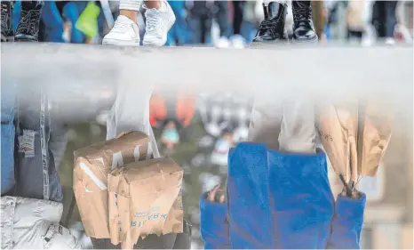  ?? FOTO: SEBASTIAN GOLLNOW/DPA ?? Passanten spiegeln sich beim Einkaufen in der Stuttgarte­r Innenstadt am Samstag in einer Pfütze: Die neuen Hilfen für die Wirtschaft summieren sich nach Schätzunge­n von Finanzmini­ster Olaf Scholz auf weitere elf Milliarden Euro.