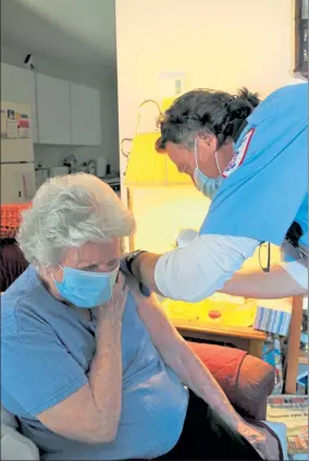  ?? DANIELLE RAY / SENTINEL & ENTERPRISE ?? Laura Begoche receives the COVID-19 vaccine at her Leominster home on Wednesday from Brewster Ambulance Service EMT Rob Barss as part of the Last Mile Vaccine Delivery mobile vaccine program.