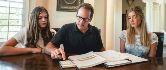  ?? KRISTINA WINDSOR/ SUN- TIMES ?? Retired Navy Cmdr. John Capizzi pores over his G. I. Bill records with daughters Raegan ( left), 14, and Cambria, 16. He fought the VA successful­ly to be able to use his benefits to pay for college for them — but many veterans aren’t so lucky.