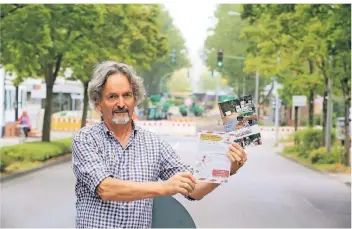  ?? FOTO: UWE MISERIUS ?? Gut informiert: Buchhändle­r Manfred Gottschalk zeigt die Flyer der Schlebusch­er Händler, die über die Baustelle auf der Oulustraße aufklären.