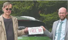  ??  ?? Tomas Manasek, left, holds his FREE AB plate with lawyer James Kitchen.