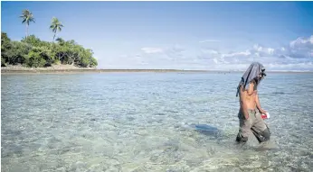  ??  ?? RISING FEAR: A man walks in the water between islets on the atoll near Majuro.