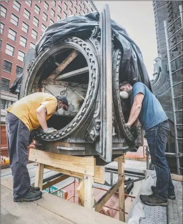  ?? (The Indianapol­is Star/Michelle Pemberton) ?? Artists and restoratio­n team members John Klinkose (left) and Brose Partington work to clean and restore the iconic Ayres Clock during a second restoratio­n effort in downtown Indianapol­is. The 85-year-old clock was installed on the side of the L.S. Ayres department store in 1936 at the corner of Meridian and Washington streets. The department store, which featured the Ayres Tea Room, operated from 1905 to 1992.