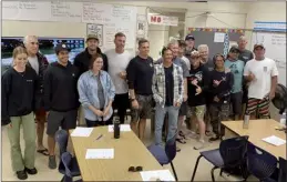  ?? The Maui News / ROBERT COLLIAS photo ?? Rich Pierce (center, white shirt), who was the co-head surf judge at the 2020 Tokyo Olympics, poses for a photo with clinic attendees after hosting Sunday’s session at Maui High School in Kahului.