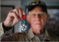  ??  ?? Tom Rice, who was an Army paratroope­r in the 101st Airborne Division and veteran of the D-Day landings in Normandy to liberate France during World War II, holds up the French Legion of Honour, which he received from the French government, at his home in Coronado on May 28.