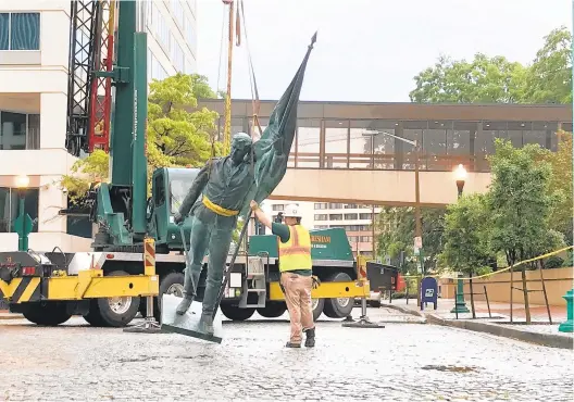  ?? GORDON RAGO/STAFF ?? Contractor­s remove the bronze statue of a Confederat­e soldier at the downtown Norfolk monument last June.