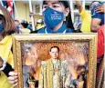  ??  ?? A royalist protester holds a framed picture of the late Thai king Bhumibol Adulyadej