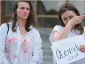  ?? ALEXEY FURMAN/GETTY ?? The fiancee of a member of the Azov Regiment wipes away a tear as another woman looks on during a rally Monday in Zhytomyr, Ukraine, west of Kyiv.