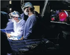  ??  ?? Sunil Singhal, second from right, directs a camera to view a tumour in his patient made visible with a fluorescen­t dye, seen in the monitor on right.