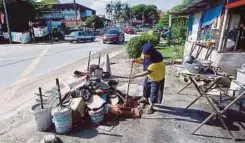  ??  ?? ROHANI Ambiah mengumpulk­an sampah di depan gerainya.