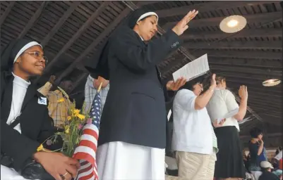  ?? DANA JENSEN THE DAY ?? Sister Jessy, second from left, and others stand to take the Oath of Allegiance to become U.S. citizens while Sister Tizy, left, watches during a Flag Day naturaliza­tion ceremony at Mystic Seaport Thursday. The sisters, originally from India, are now...