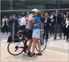  ?? KATHLEEN CAREY - MEDIANEWS GROUP ?? Price Burlington receives a hug from his wife, Joretta, while SAP employees applaud the conclusion of his crosscount­ry bike tour.