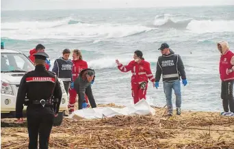  ?? Antonino Durso/Associated Press ?? Italian Red Cross volunteers and coast guards recover a body after a migrant boat broke apart in rough seas, at a beach near Cutro, southern Italy, on Sunday.