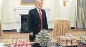  ?? REUTERS ?? ■ President Donald Trump looks over tables of fast food.