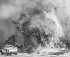  ?? (AP) ?? Flames from the Carr Fire lick above a Cal Fire truck in Whiskeytow­n, California on Friday.