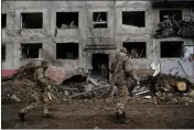  ?? LYNSEY ADDARIO — THE NEW YORK TIMES ?? Ukrainian soldiers walk past a crater in front of a high-rise building on Sunday in the aftermath of a missile attack in Druzhkivka, just west of Bakhmut.
