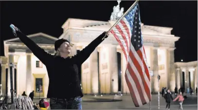  ?? Markus Schreiber The Associated Press ?? American Marianne Hoenow celebrates the victory of President-elect Joe Biden and Vice President-elect Kamala Harris in front of the Brandenbug Gate in Berlin on Saturday. German Chancellor Angela Merkel and many other world leaders congratula­ted Biden.