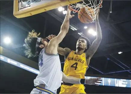  ?? Ringo H.W. Chiu Associated Press ?? UCLA’S JAIME JAQUEZ JR., left, dunks for two of his 26 points as Arizona State’s Desmond Cambridge Jr. defends during the second half of their Pac-12 game. Jaquez scored 19 points in the first half as the fourth-ranked Bruins pulled away for their ninth win in a row.