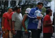  ?? REBECCA BLACKWELL — THE ASSOCIATED PRESS ?? Men line up for donated drinking water, after scores of Central American migrants, representi­ng the thousands participat­ing in a caravan trying to reach the U.S. border, undertook an hours-long march to the office of the United Nations’ humans rights body in Mexico City.