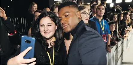  ?? THE ASSOCIATED PRESS ?? The Last Jedi cast member John Boyega poses with Olivia Sava, 14, at the première of the film at the Shrine Auditorium in Los Angeles. Sava, who has a form of leukemia, was among seven teens with life-threatenin­g illnesses who had their Star Wars...