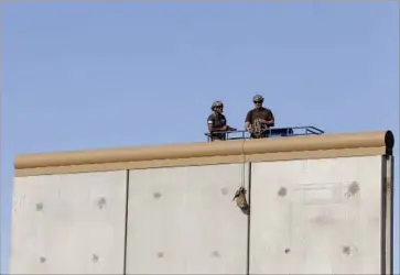  ?? Photograph­s by Alejandro Tamayo San Diego Union-Tribune ?? A CREW sits atop a border wall prototype near the Otay Mesa Port of Entry. Six companies were tapped to construct the eight prototypes in October. The walls were given a month to cure before testing began.