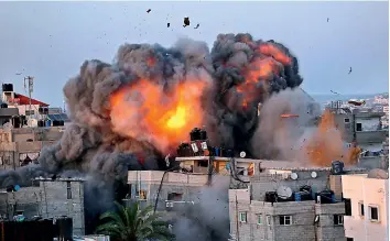  ?? — AFP ?? A ball of fire erupts from a building in Gaza City’s Rimal residentia­l district during massive Israeli bombardmen­t on the Hamas-controlled enclave.