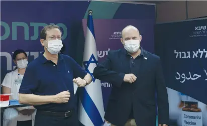  ?? (Maya Alleruzzo/Reuters) ?? PRESIDENT ISAAC HERZOG bumps elbows with Prime Minister Naftali Bennett after he received a third COVID-19 vaccine dose in July at Sheba Medical Center in Ramat Gan.