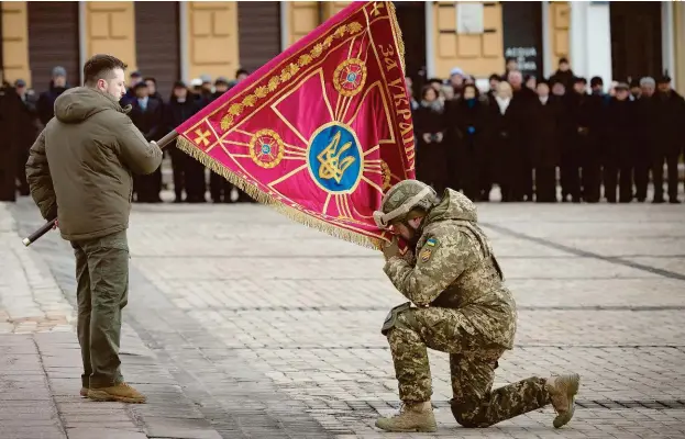  ?? AFP ?? Un soldado ucraniano besa una bandera izada por el presidente Volodimir Zelenski durante la conmemorac­ión de la invasión rusa